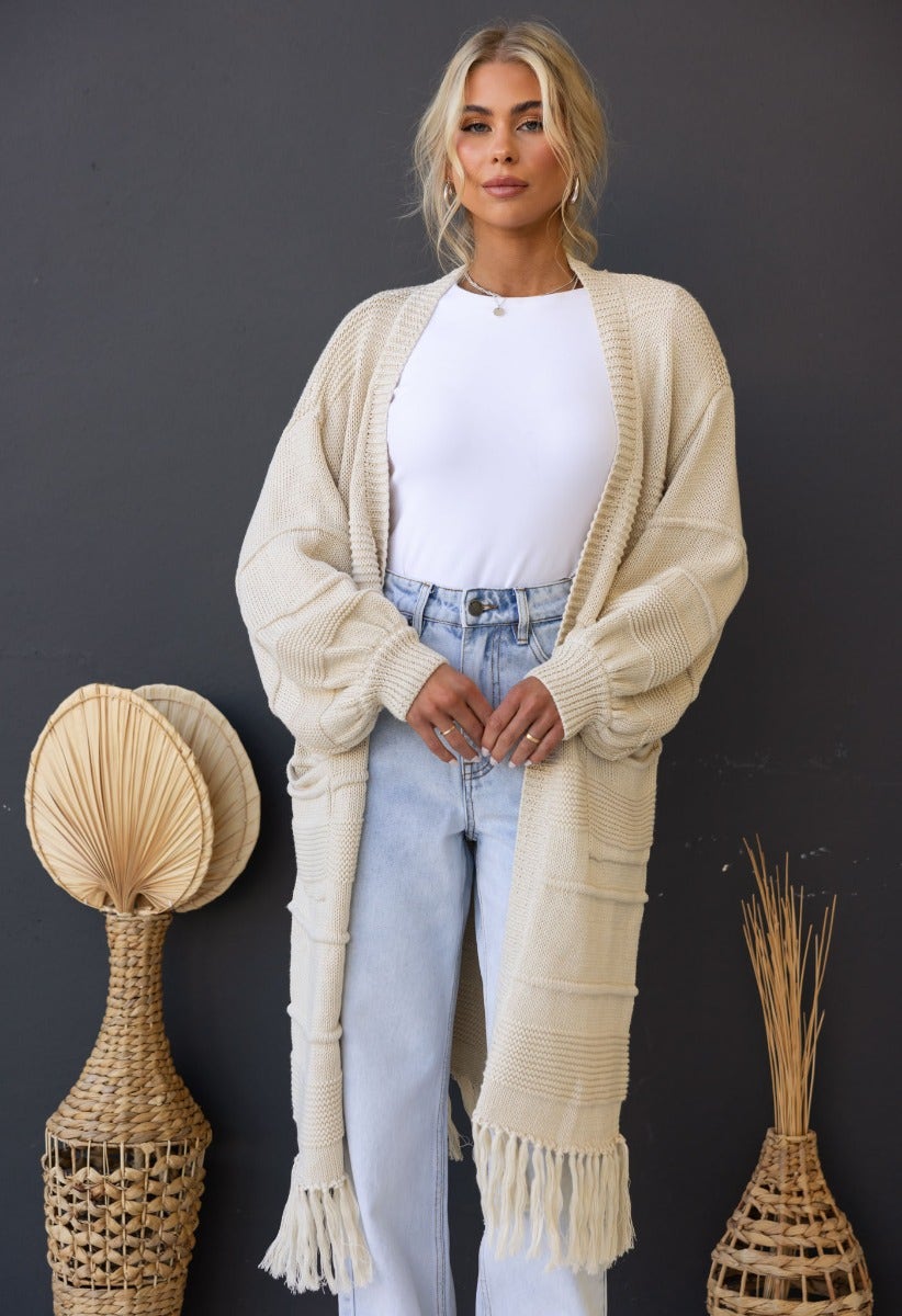 Zeddie Cardigan in cream, longline knit style, featuring pockets and a relaxed fit, worn with high-waisted jeans.