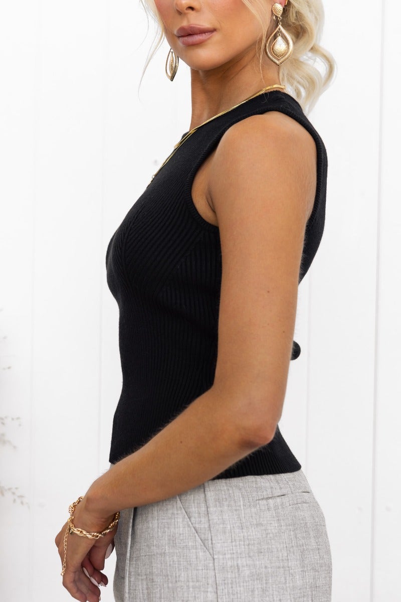 Side view of a woman in a black ribbed Morgan Top, showcasing its high neckline and standard fit.