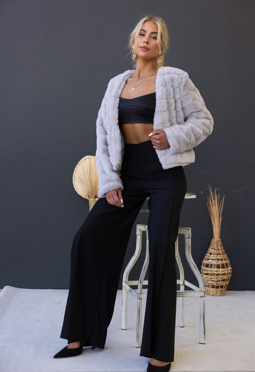 Model wearing Aviana Jacket, a faux fur jacket, styled with a black crop top and pants, perfect for a chic look.