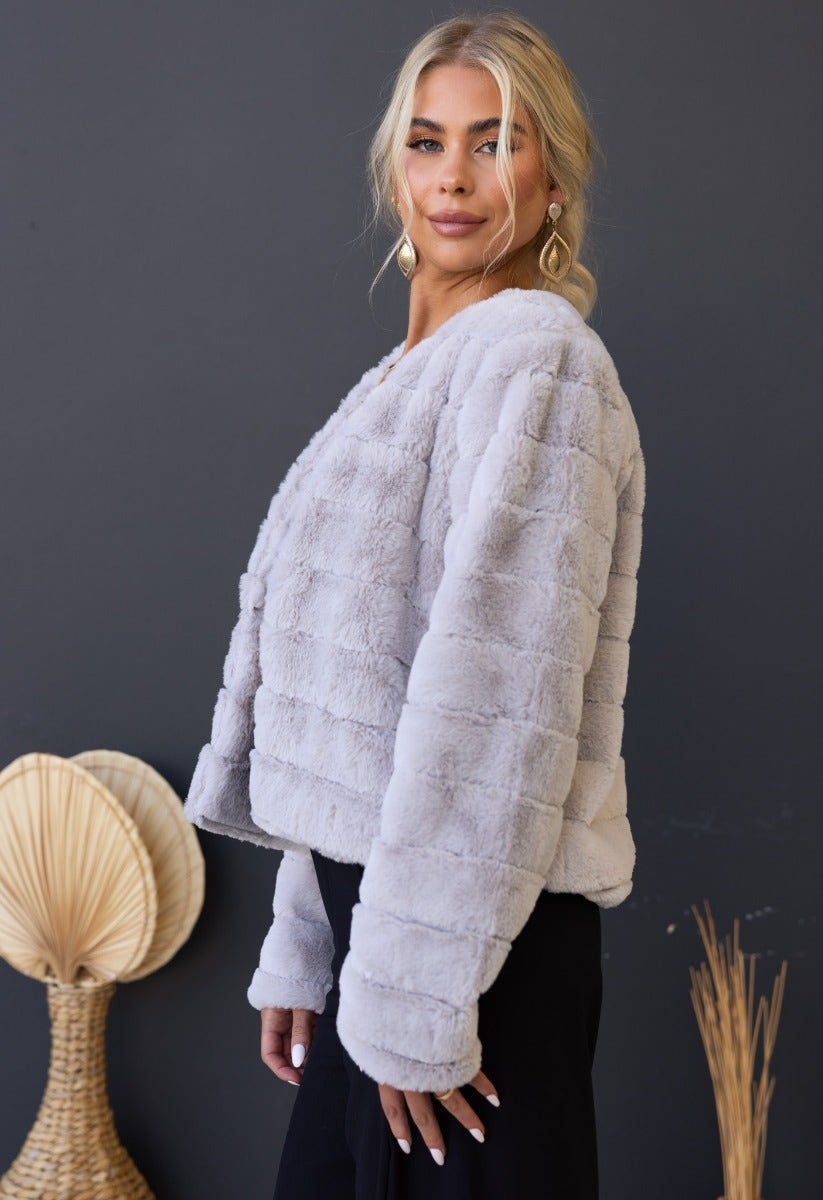 Model wearing the Aviana Faux Fur Jacket in light gray, showcasing its cozy texture and stylish design.