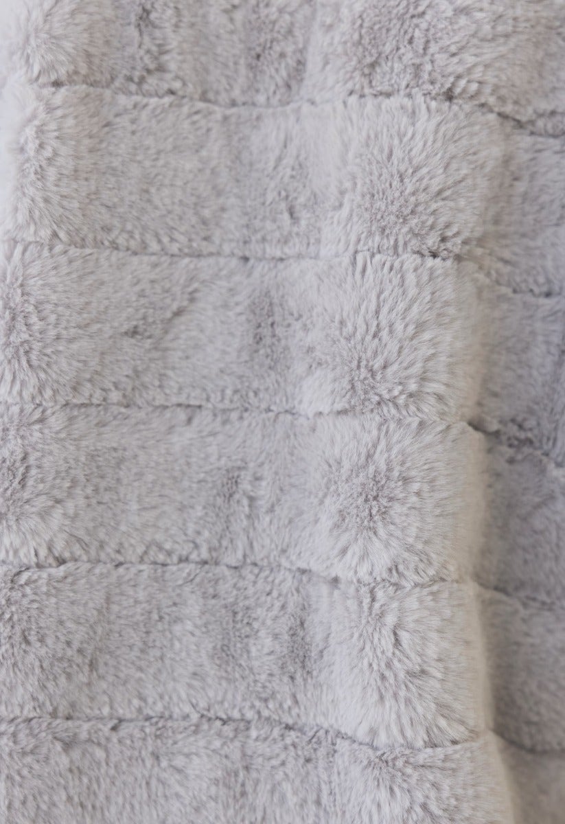 Close-up of soft faux fur fabric featuring a textured striped pattern in light gray.