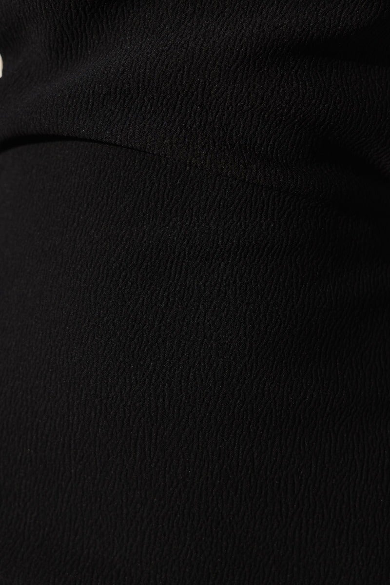 Close-up of the textured black fabric of the Feeling You Dress, showcasing its unique material and elegant design.