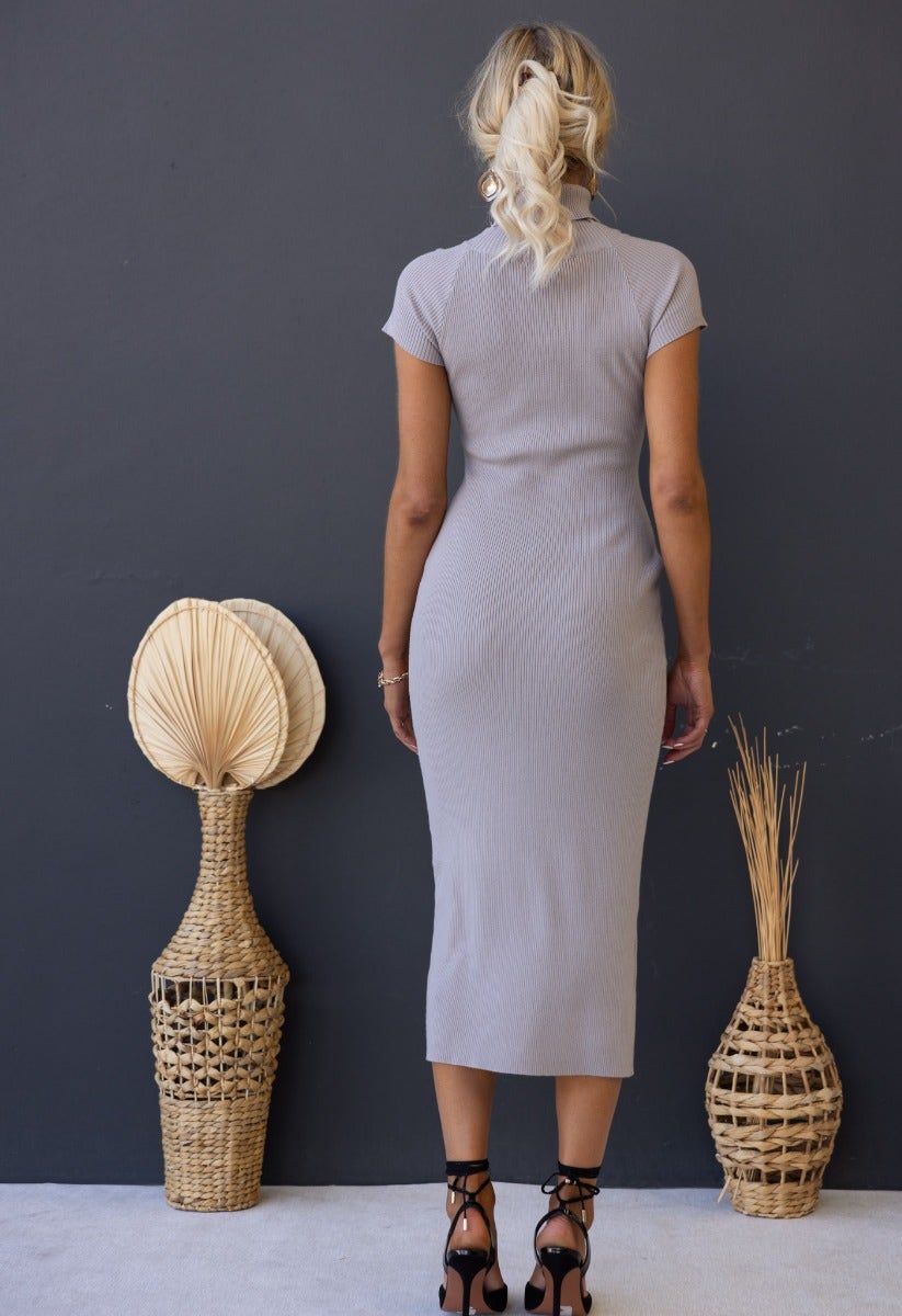 Back view of woman wearing a grey ribbed knit Ulina Midi Dress, styled with boho decor.