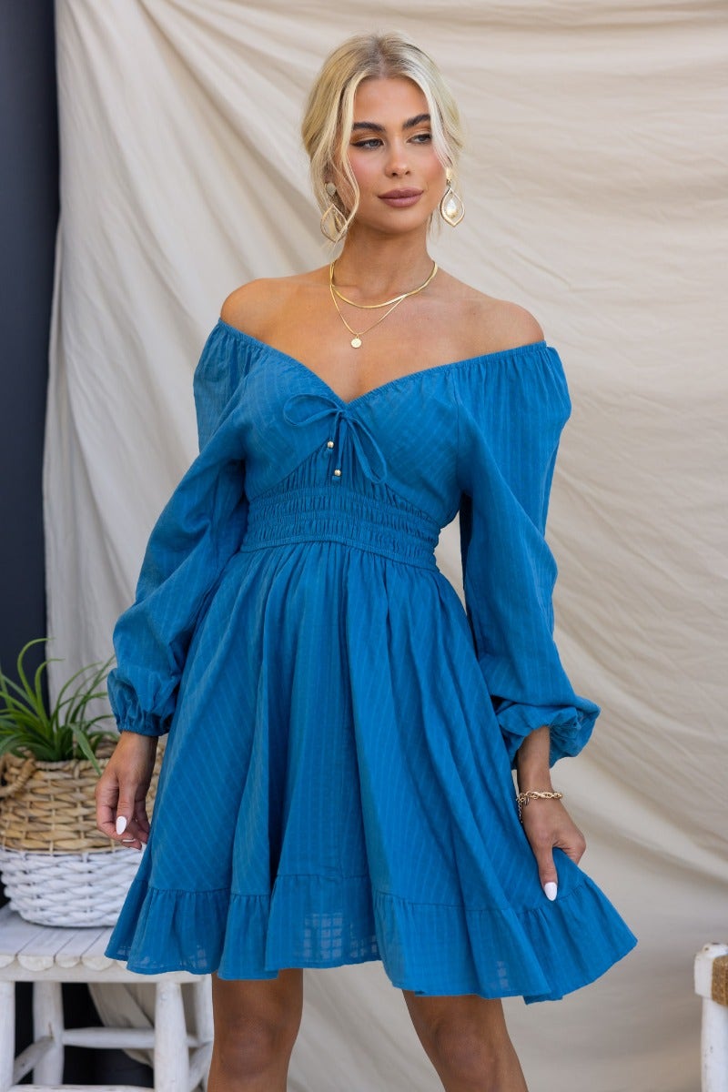 Blue cotton getaway dress with elastic sleeves, tie neckline, and flared skirt, showcased in casual styling.