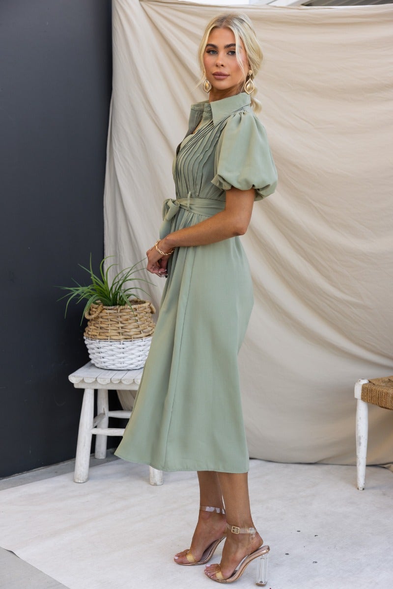 Model wearing a Sorrento Midi Dress in green with high neckline, button-up front, and pleated detail.
