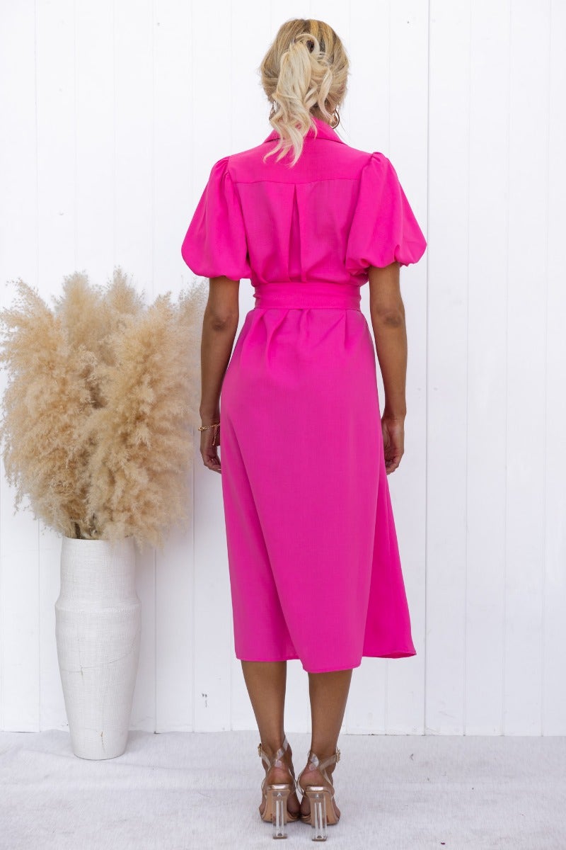Back view of a model in a bright pink Sorrento midi dress with puff sleeves and a removable belt.