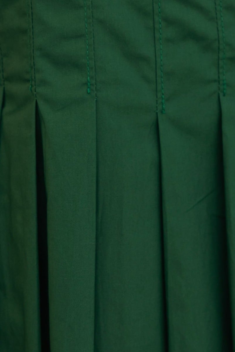 Close-up of green pleat detail on a cotton blend maxi dress, showcasing fabric texture.