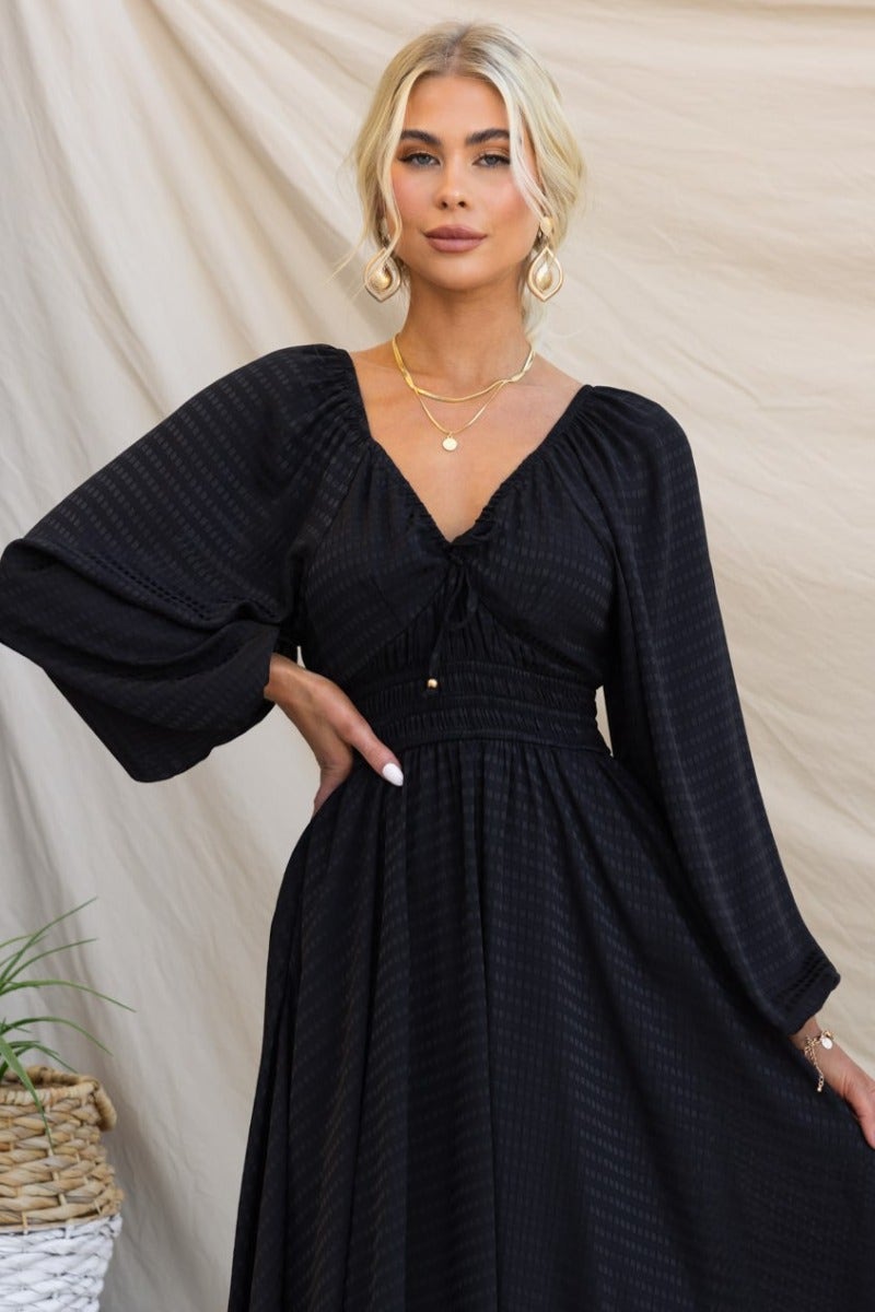 Elegant black cotton getaway dress with elastic sleeves and tie neckline, perfect for stylish occasions.