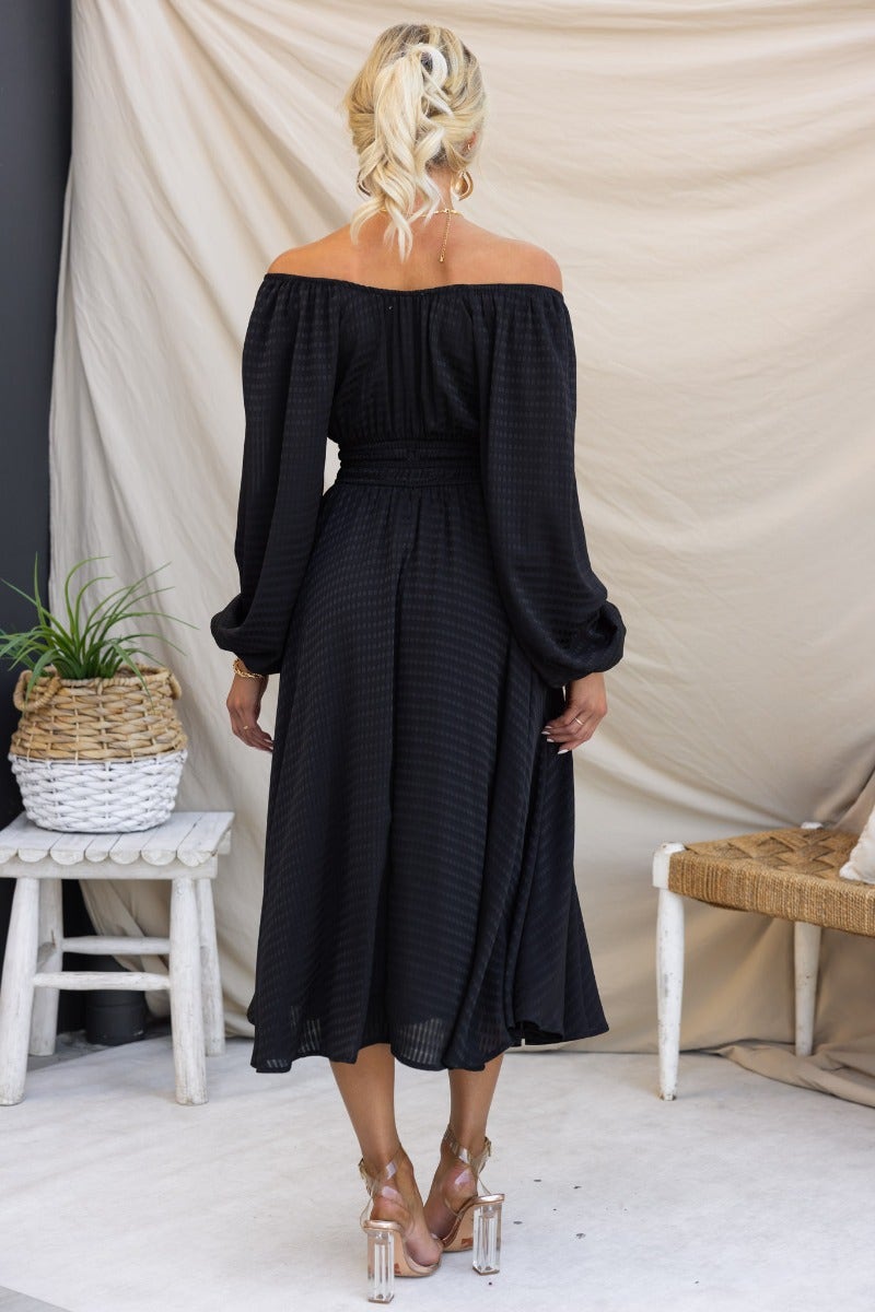 Kyrie Midi Dress in black, textured material with off-shoulder design, elastic fittings, and tie neckline detail.