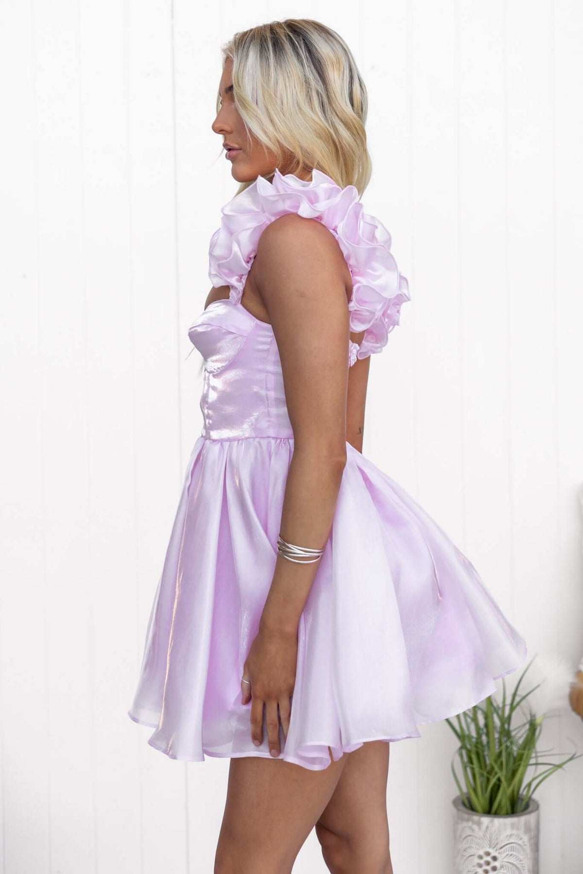 Model wearing the Ermia Dress, featuring ruffle straps and a shiny chiffon material in soft pink.