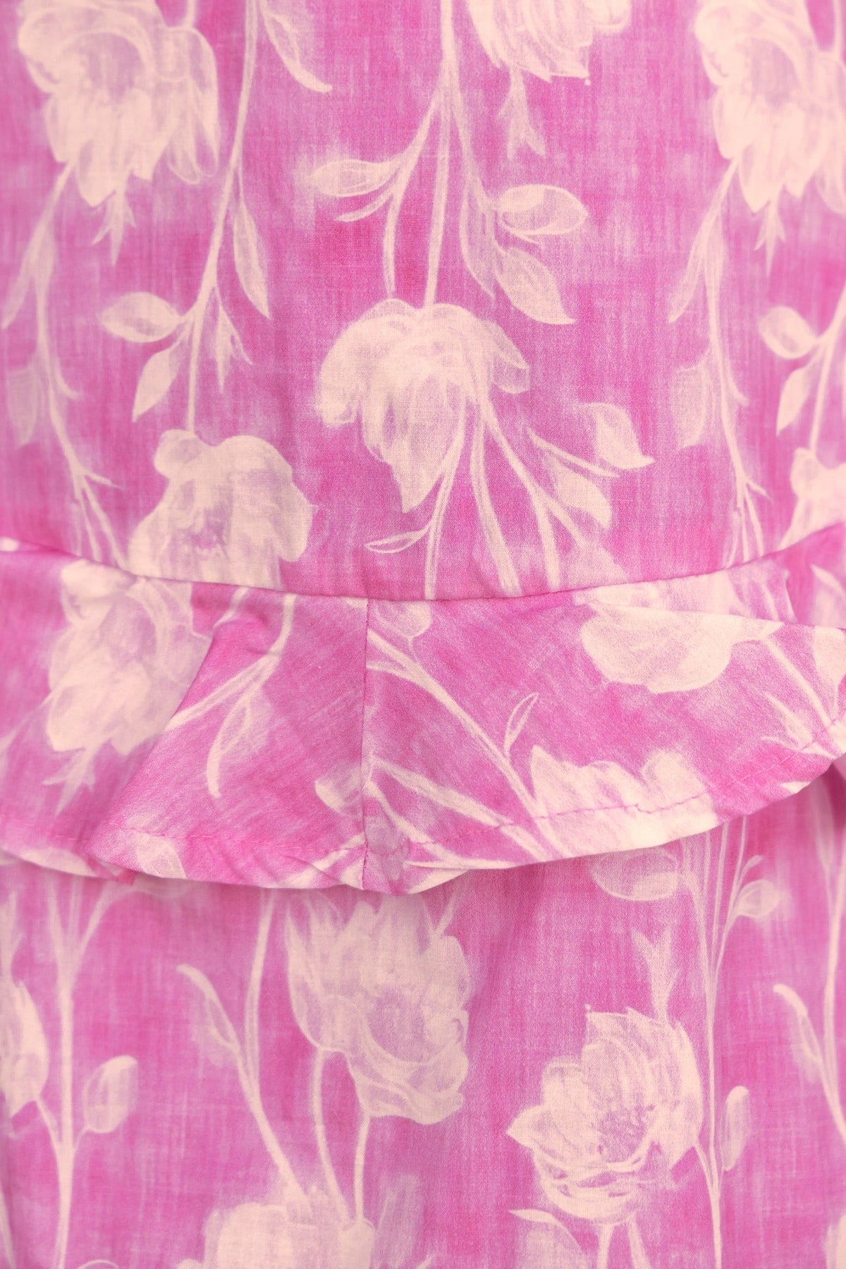 Close-up of pink floral fabric with ruffle detail on the Change Me Dress, featuring a soft cotton texture.