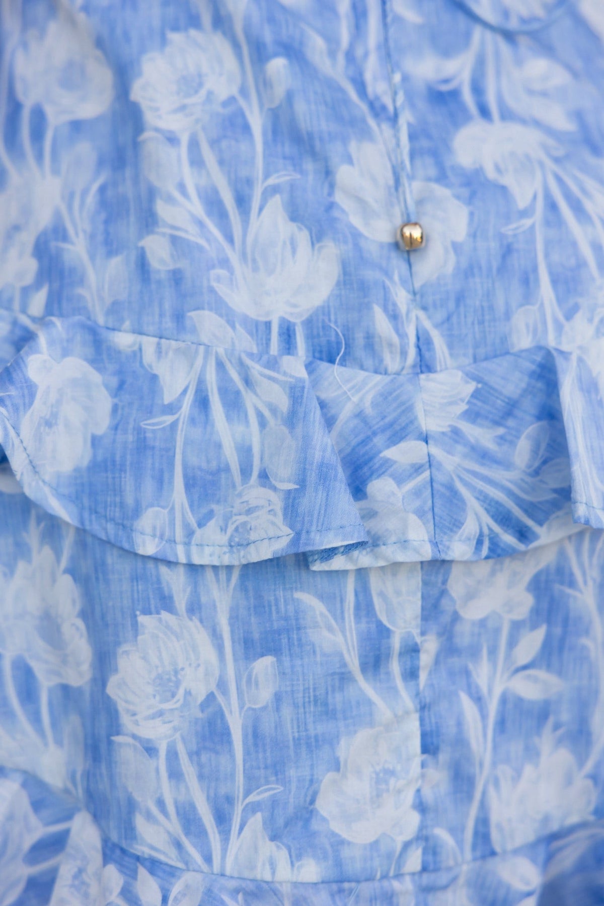 Light blue floral dress with ruffled hem and buttons, showcasing a soft cotton fabric and delicate floral pattern.