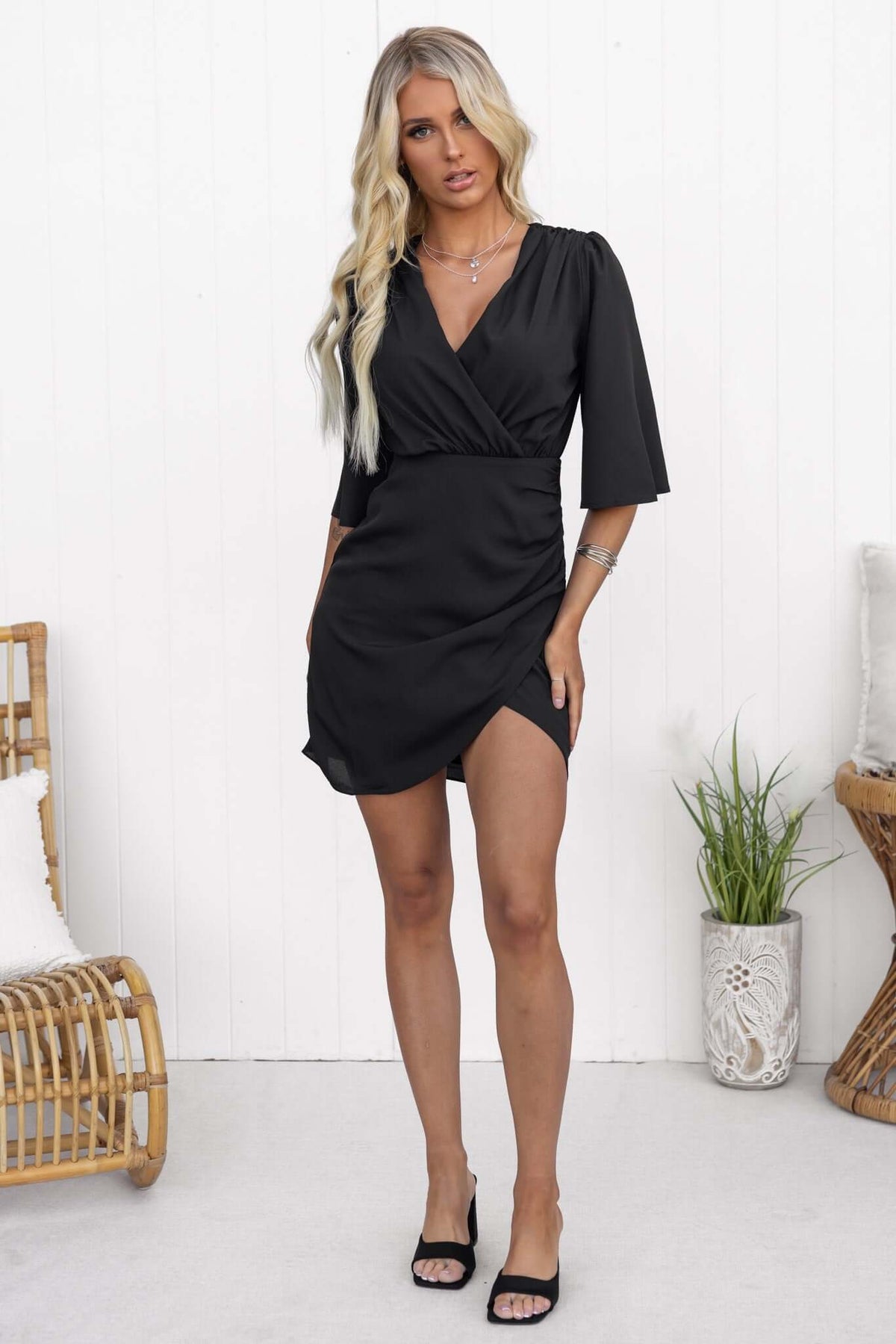 Ludlow dress in black with V-neckline and short sleeves, featuring a wrap design and a stylish slit.