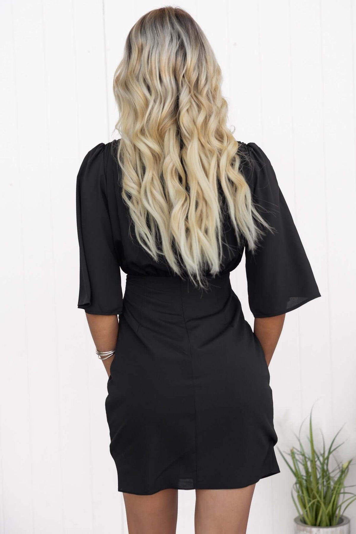 Back view of a woman in a black Ludlow Dress with puff sleeves, showcasing its sleek, fitted design.