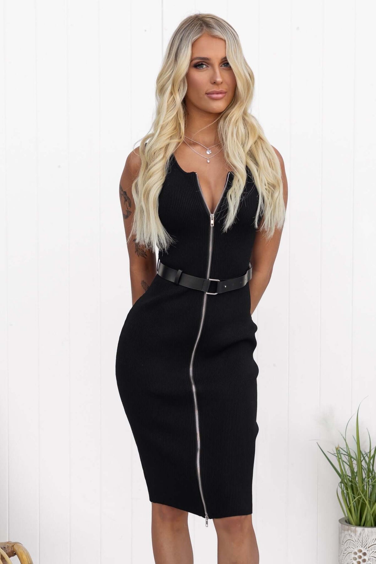 Model wearing a black Rawlins dress with a zip-up front and removable belt, showcasing a standard fit.