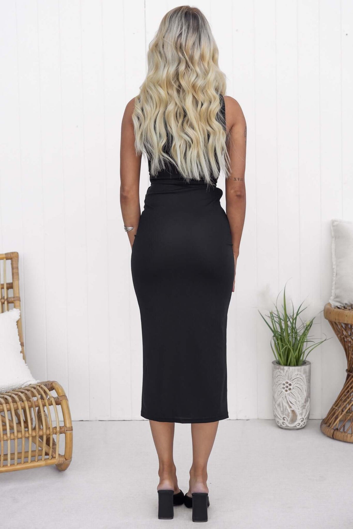 Back view of a woman in a black Grazia Midi Dress, featuring a high neckline and fitted silhouette.