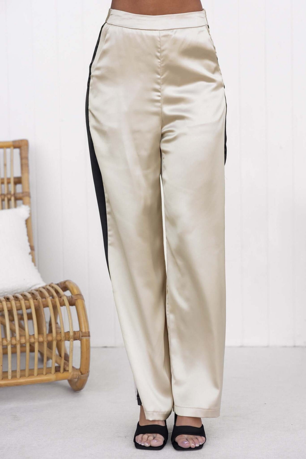 Tanaya Pants featuring a mid-high waist, satin texture, side pockets, and invisible zip, styled with strappy heels.