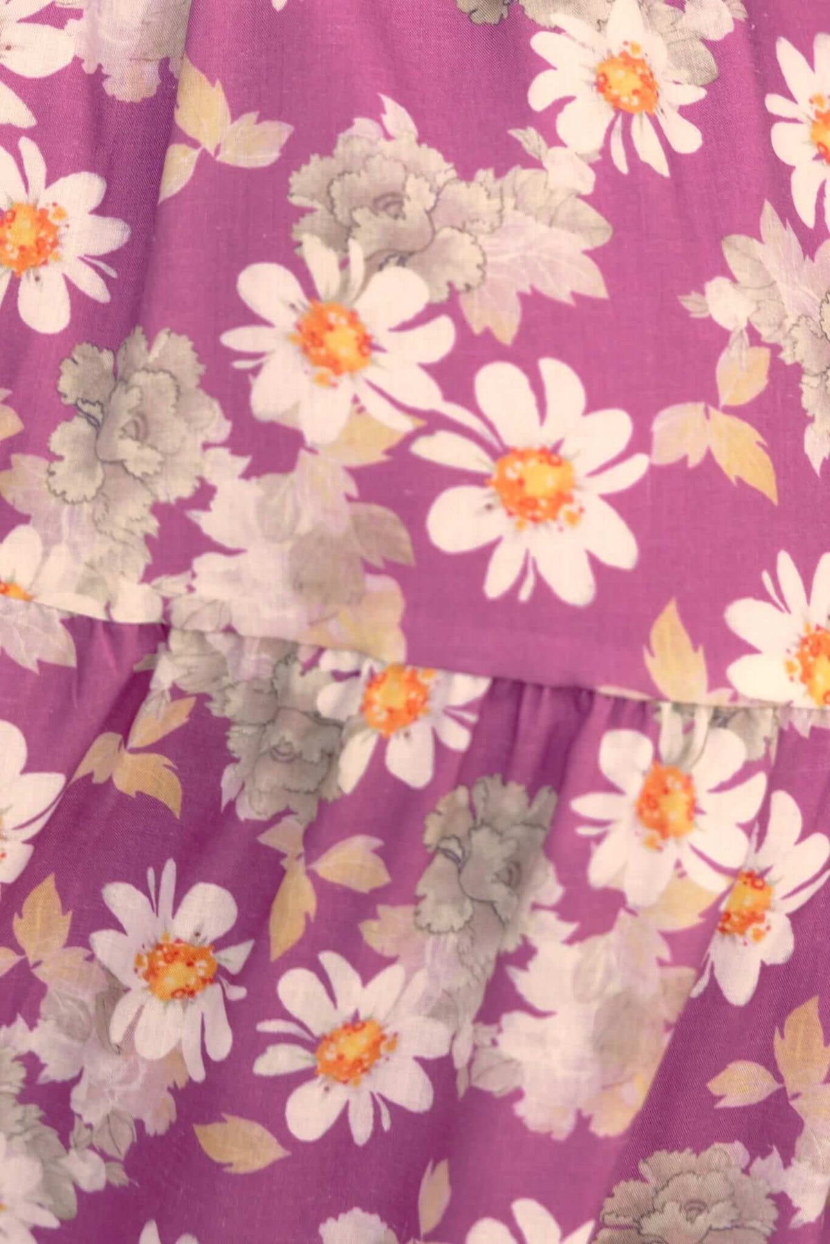 Close-up of a floral pattern in purple fabric featuring white daisies and gray flowers, perfect for a midi dress design.