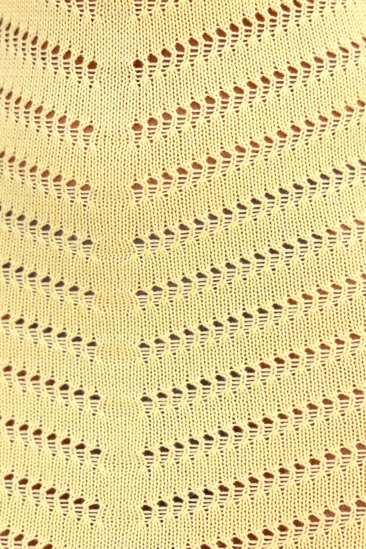 Close-up of open weave pattern in yellow fabric, showcasing intricate chevron design and flexibility.
