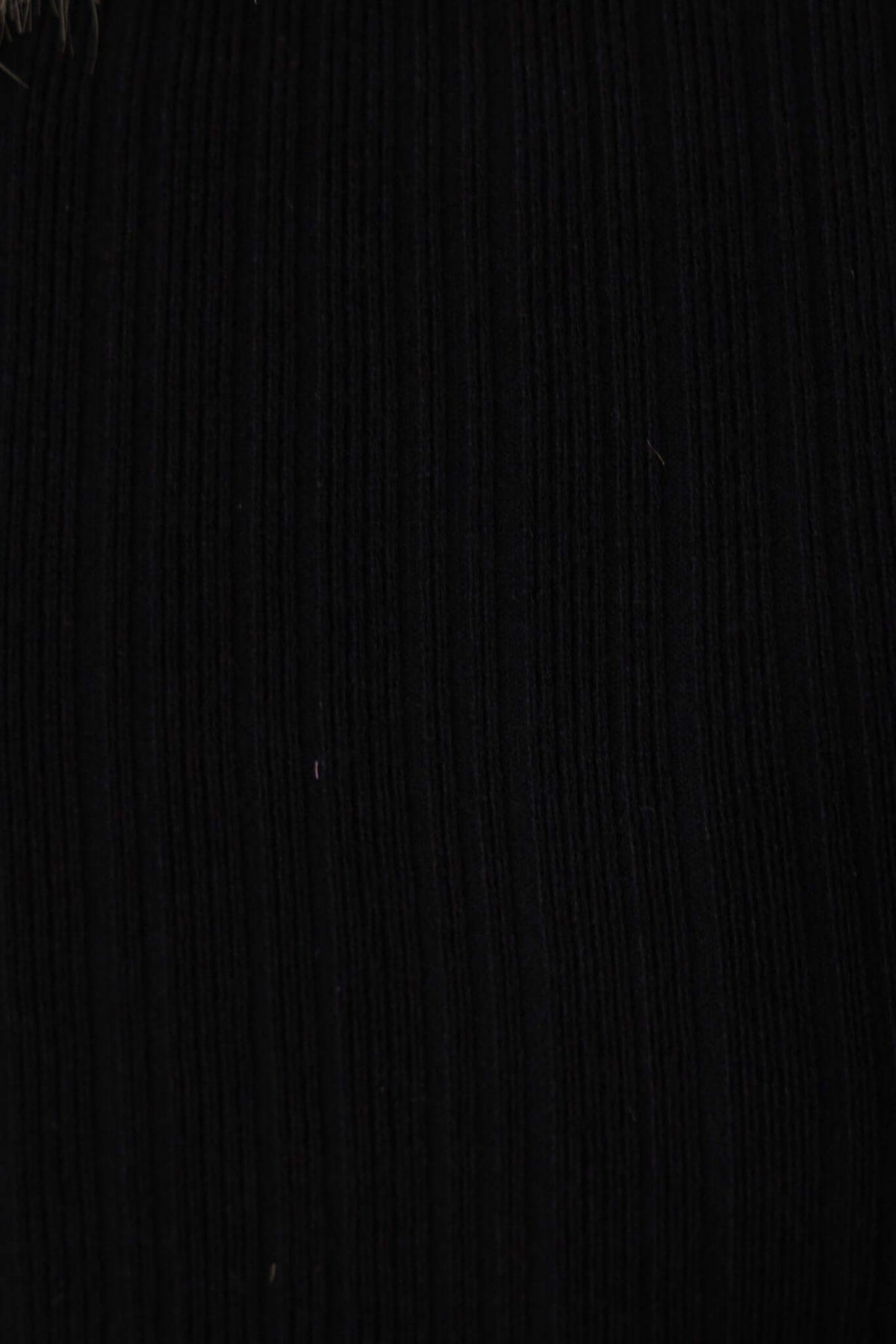 Close-up of a black ribbed knit fabric, showcasing its texture for the Ollie Top, featuring high neckline and stretch material.
