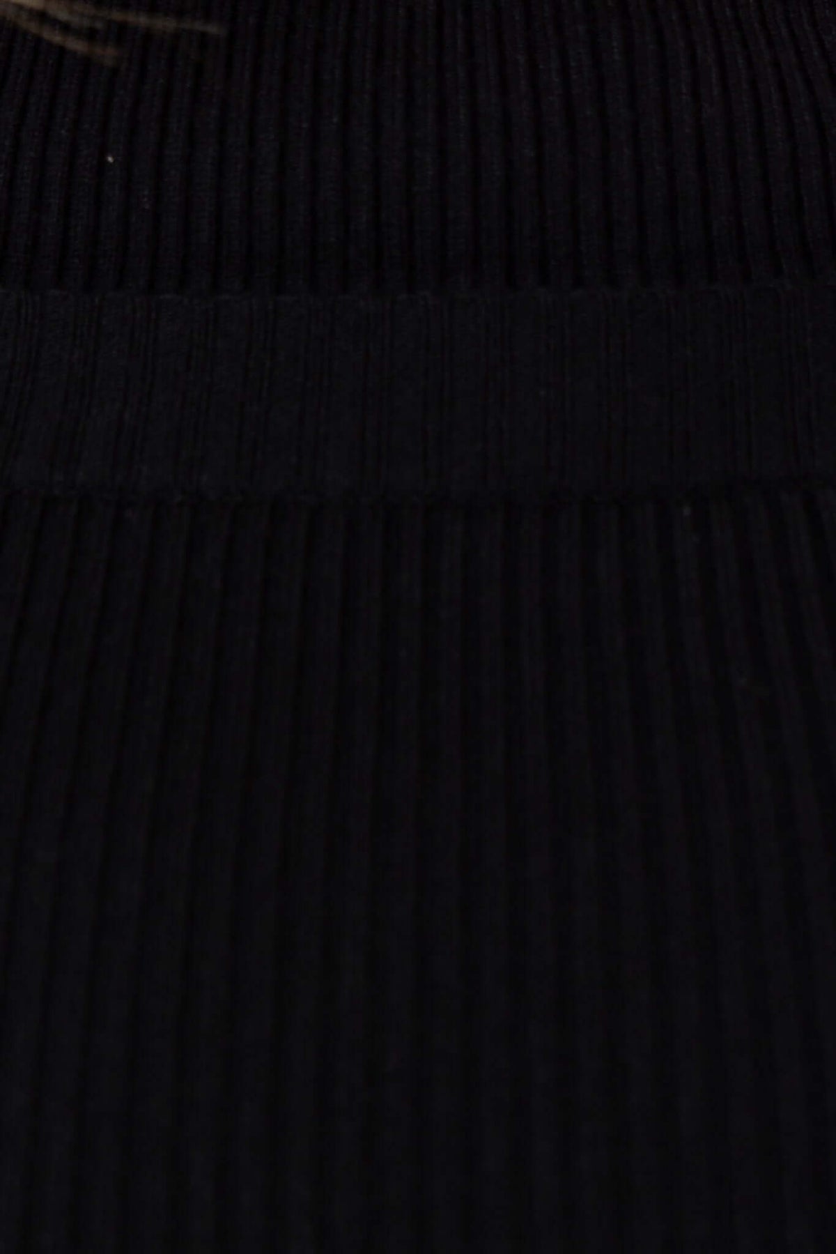 Close-up of black ribbed knit material showcasing the texture of the Vada Top, featuring a stretchy design.