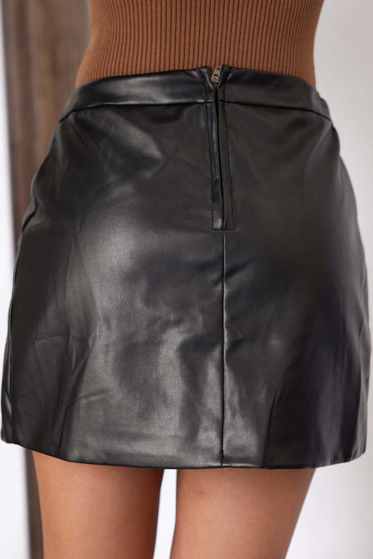 Black faux leather Rolla skirt featuring a mid-high waist fit and zip closure at the back.