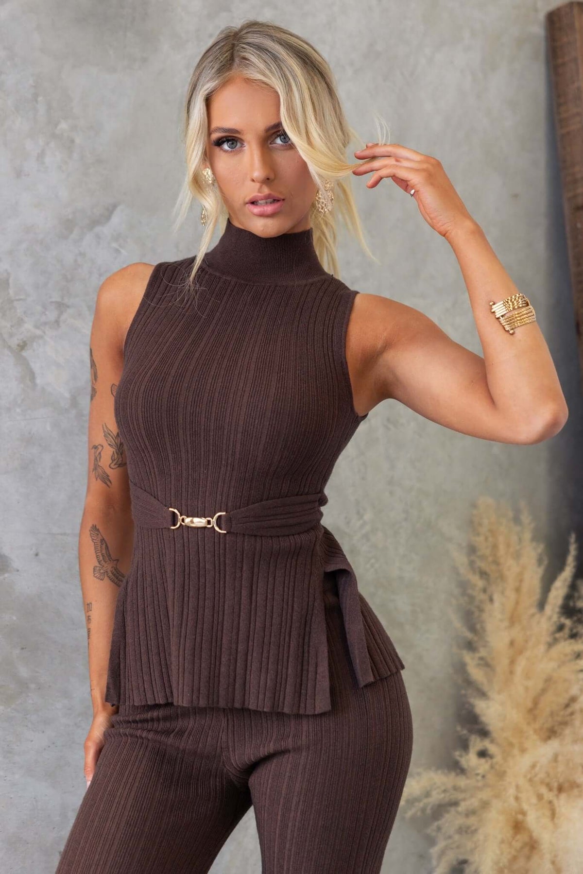 Brown ribbed knit Burling top with high neckline, back tie, and gold buckle detail, featuring stylish front splits.