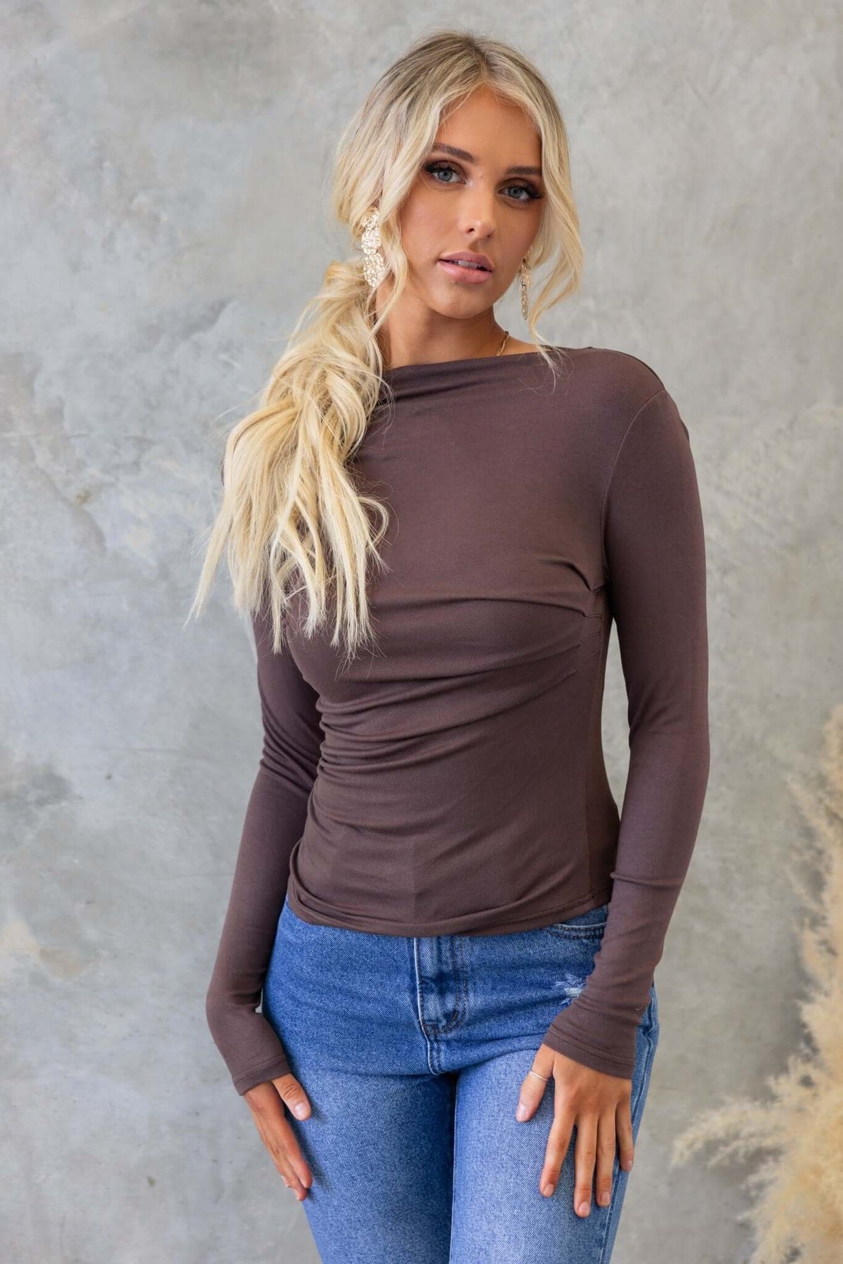 Stylish model wearing the Iletta Top with boat neckline and stitched detail, paired with denim jeans.