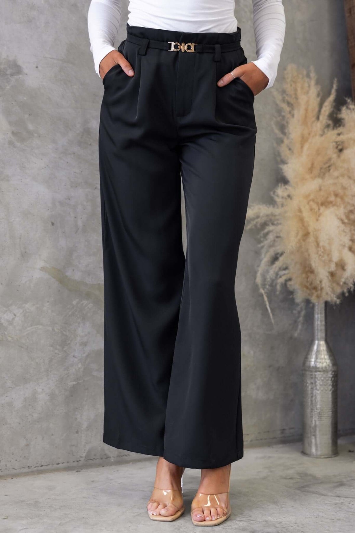 Model wearing black Hammond pants with mid-high waist and removable belt, styled with a white long-sleeve shirt.