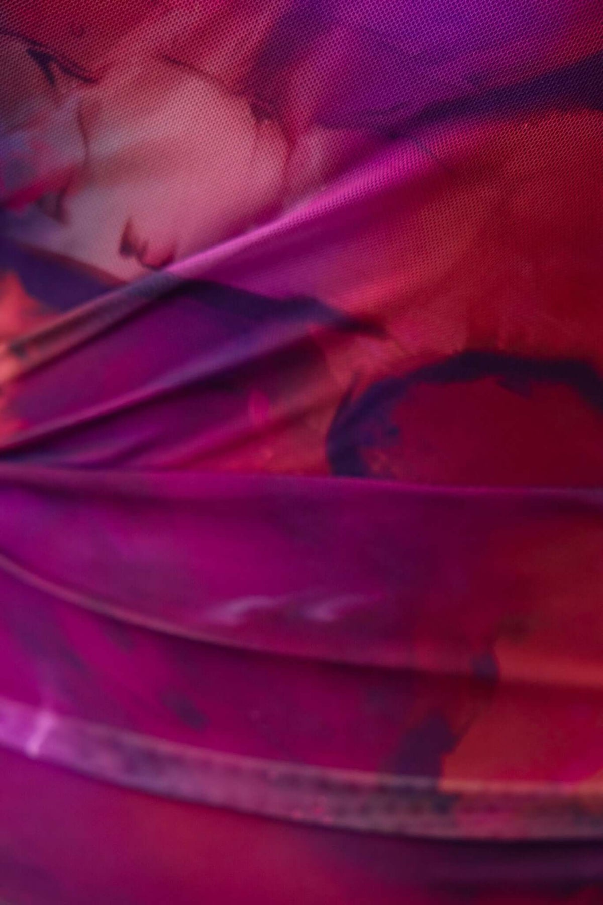 Close-up of mesh overlay fabric featuring vibrant pink and purple hues, showcasing ruching details and texture.