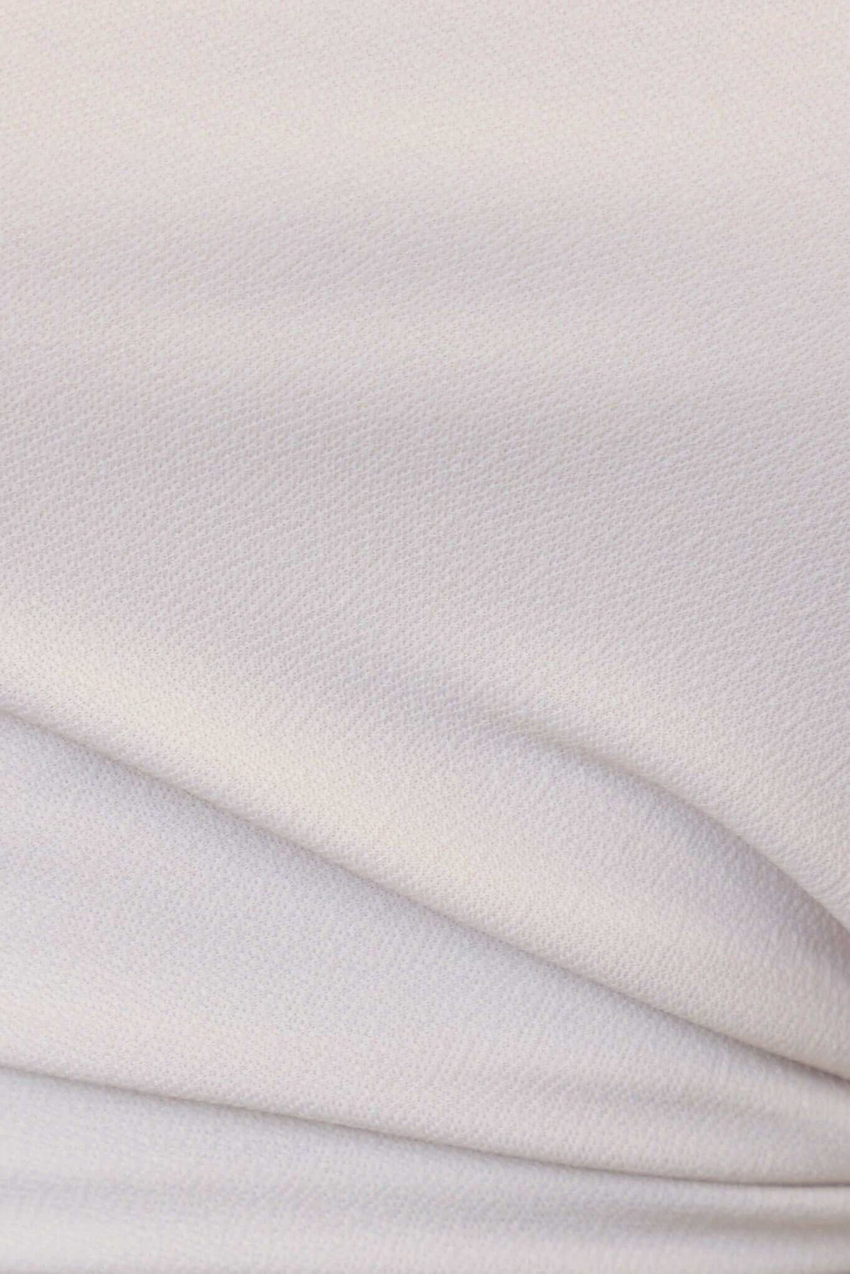 Close-up of soft, stretchable fabric of a white midi dress, showcasing its texture and smooth appearance.