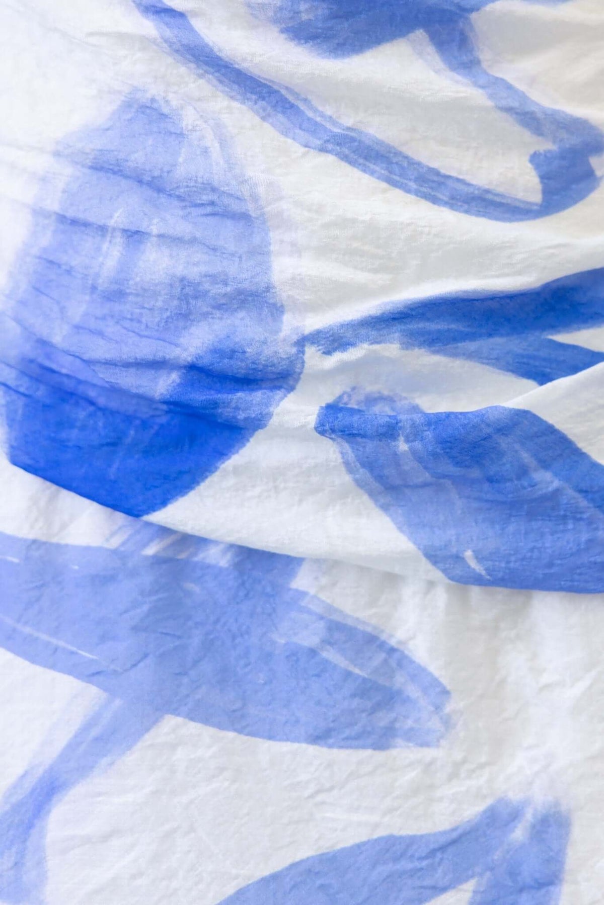 Close-up of white fabric with abstract blue brushstroke patterns, ideal for Qileen Maxi Dress detailing.