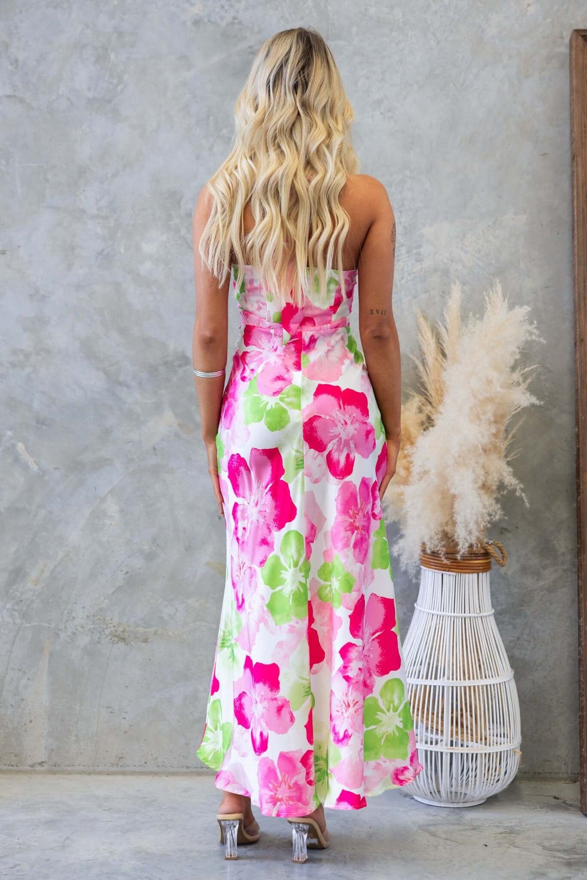 Back view of a model wearing the Forbidden Love Maxi Dress with floral print and a satin finish.