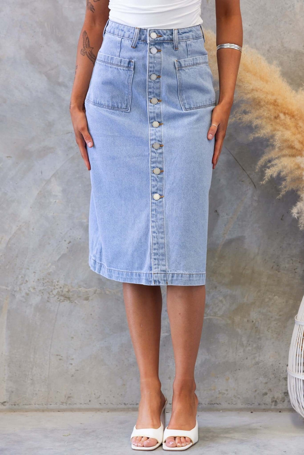 Soma Denim Midi Skirt in light blue, featuring a button-up front and pockets, styled with a fitted top and sandals.