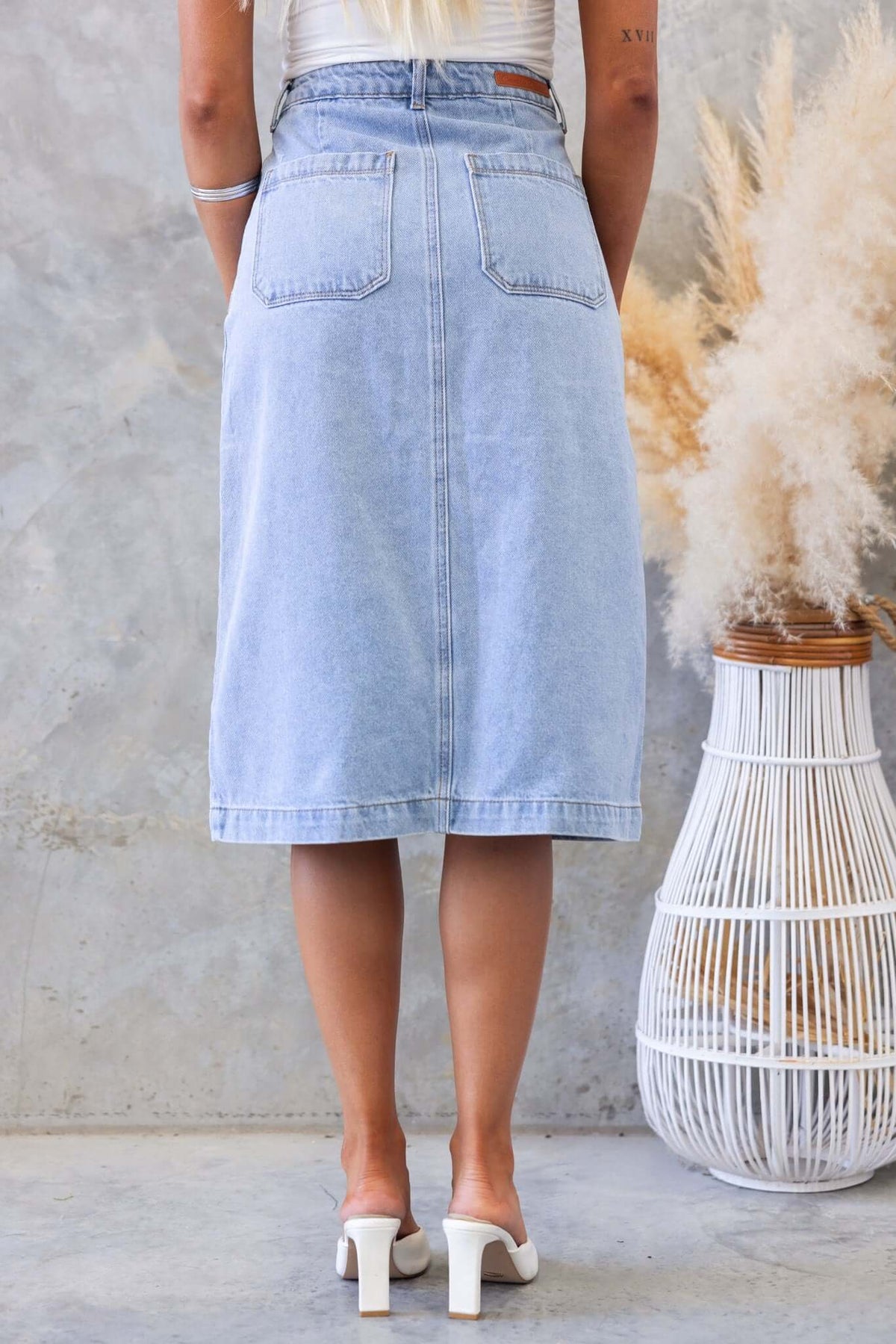 Back view of a Soma Denim Midi Skirt in light blue, featuring pockets and a mid-high waist fit.