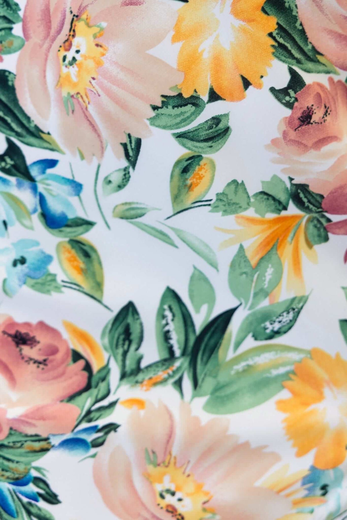 Colorful floral pattern featuring pink, yellow, and blue flowers against a white background.