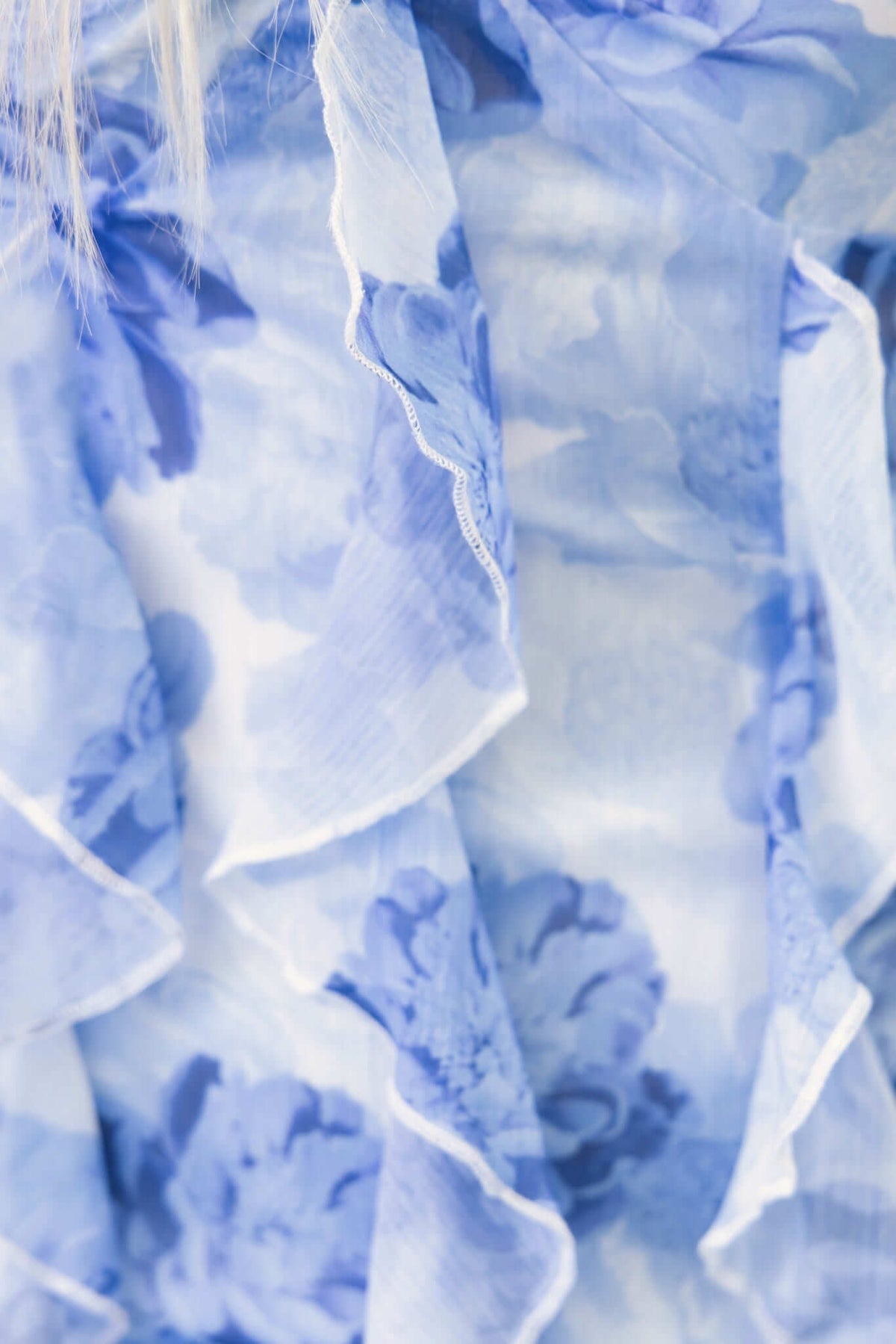 Close-up of light blue ruffled chiffon fabric featuring floral patterns, ideal for a stylish maxi dress.
