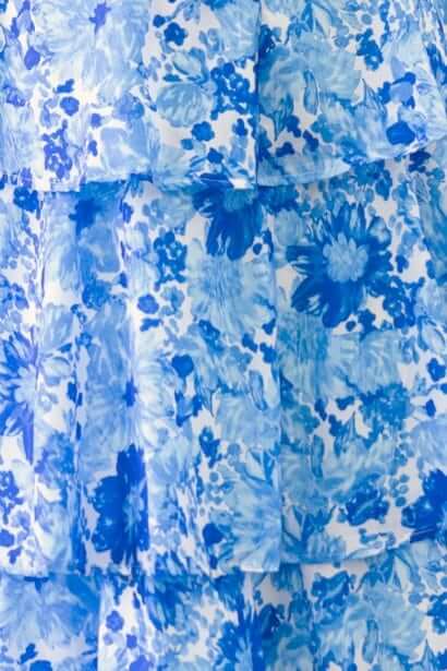 Close-up of the Peyton Maxi Dress with a vibrant blue floral print and layered ruffle skirt design.