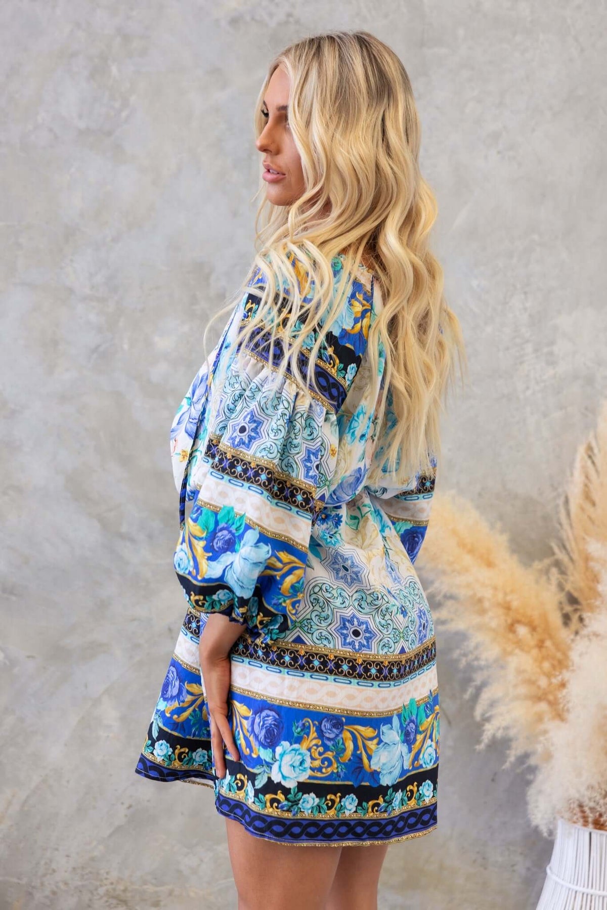 Side view of a model wearing a blue and green patterned Barret dress with a relaxed fit and V-neckline.