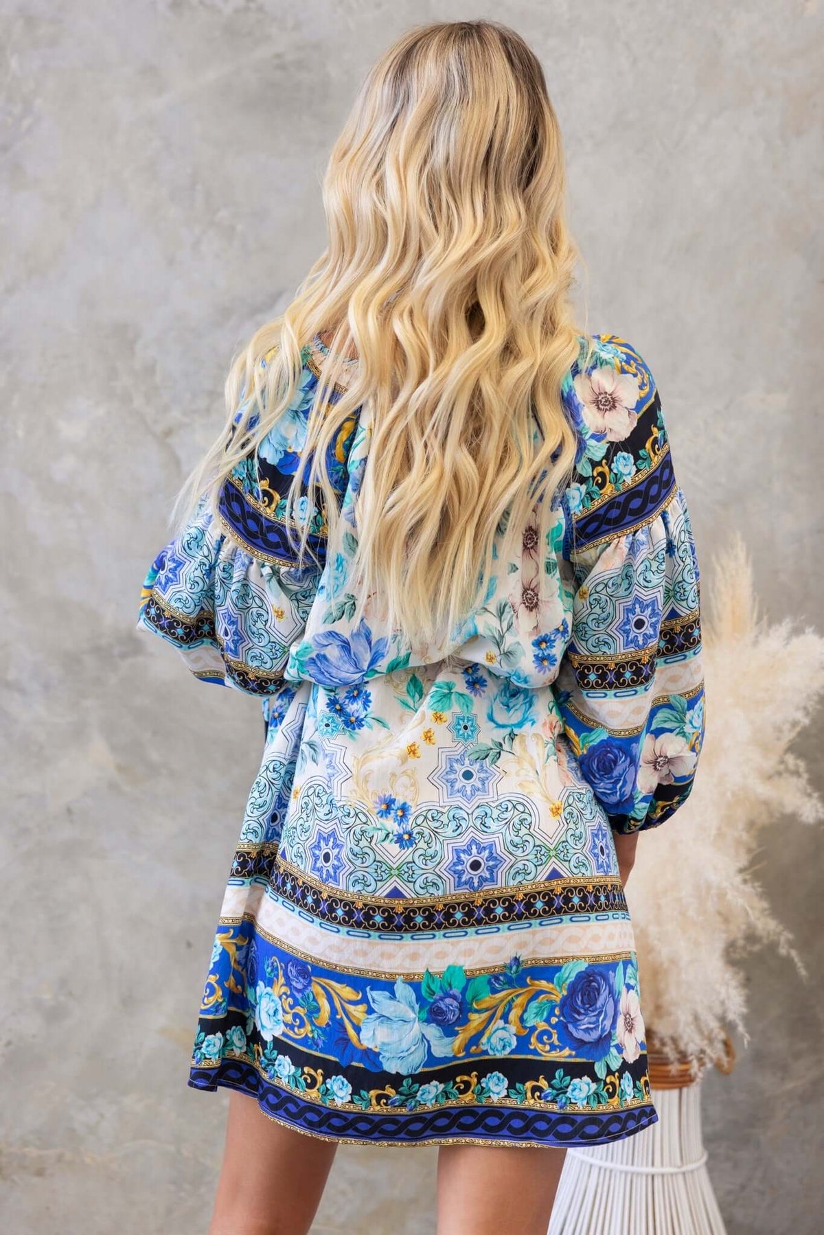 Back view of a model wearing a colorful floral Barret Dress, featuring a relaxed fit and vibrant patterns.
