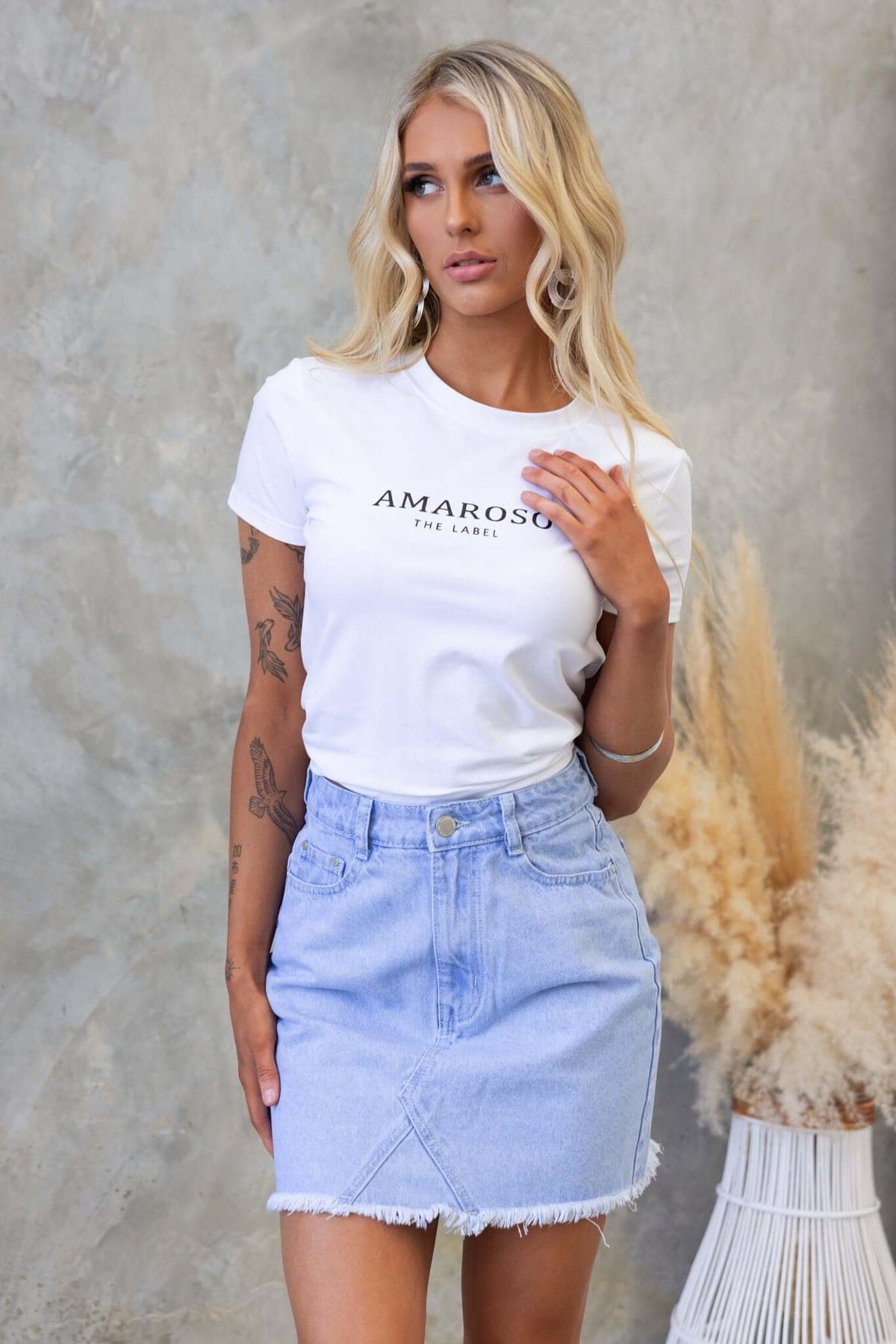 Model wearing an Amarozo white t-shirt and a light blue denim skirt with a raw hem.