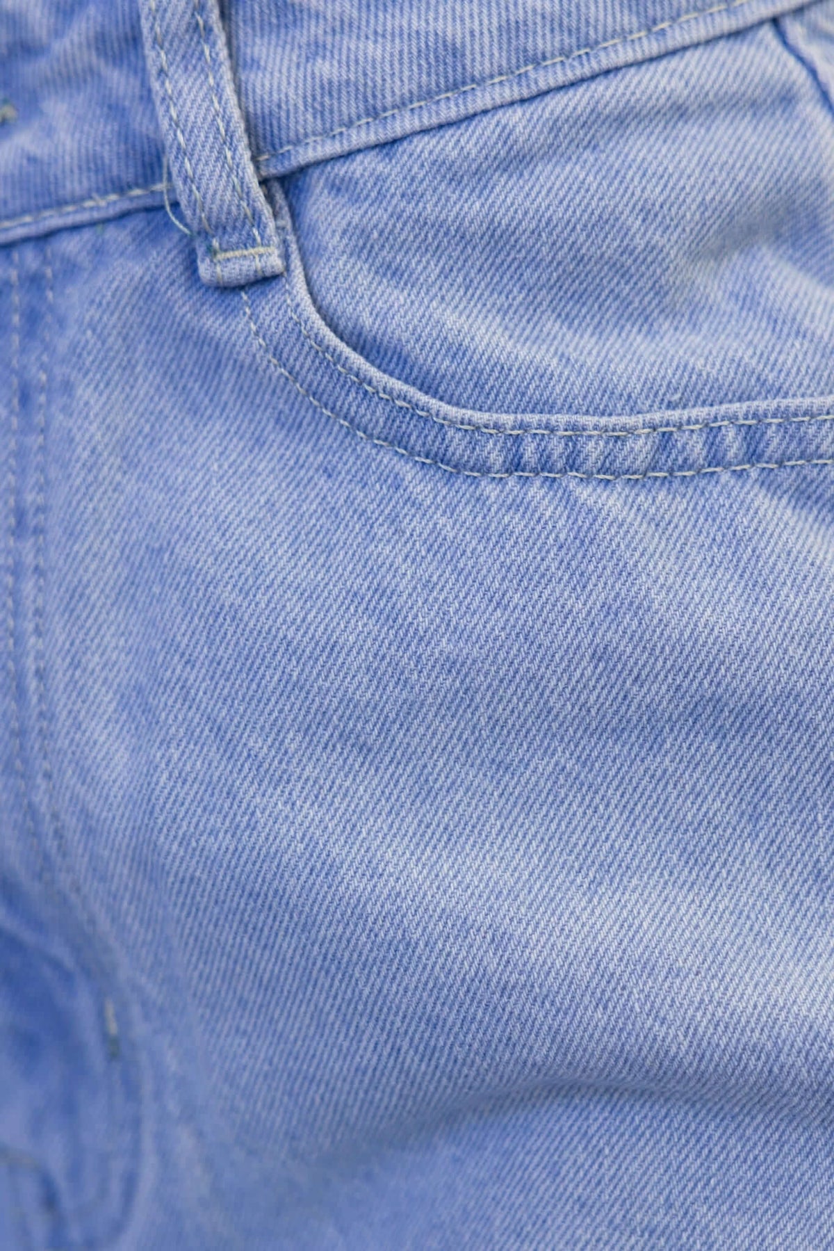 Close-up of light blue denim fabric showcasing texture and stitching details of a skirt.