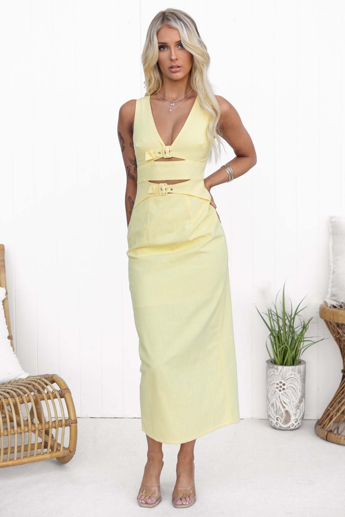 Stylish woman in a yellow Mirai Maxi Dress with V-neckline and buckle details, showcasing chic summer fashion.