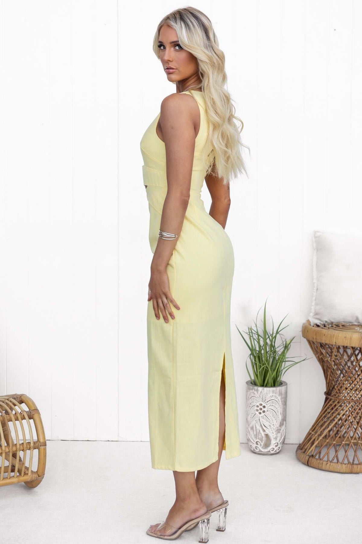 Model side view in Mirai maxi dress with V-neckline, cut-out waist, and back split in soft yellow.