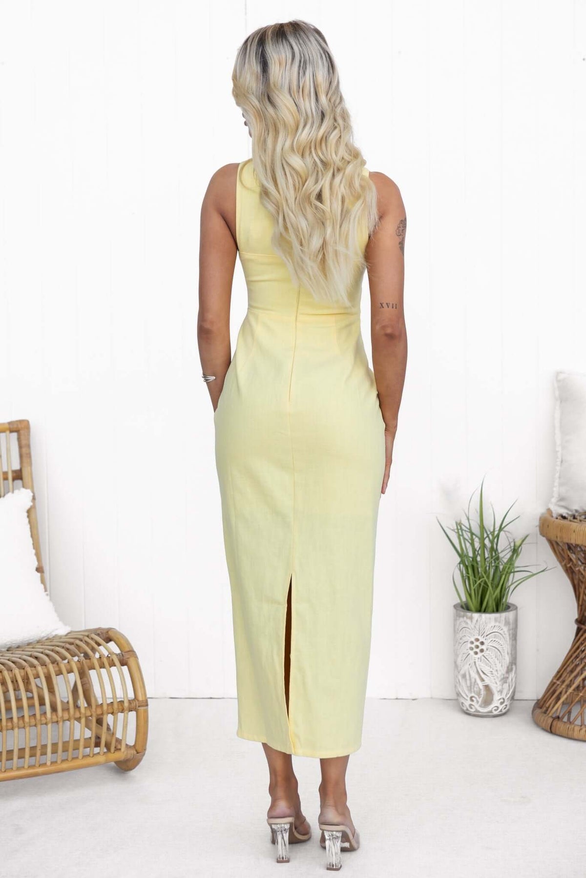 Back view of a model in a yellow Mirai Maxi Dress featuring a split and fitted design.