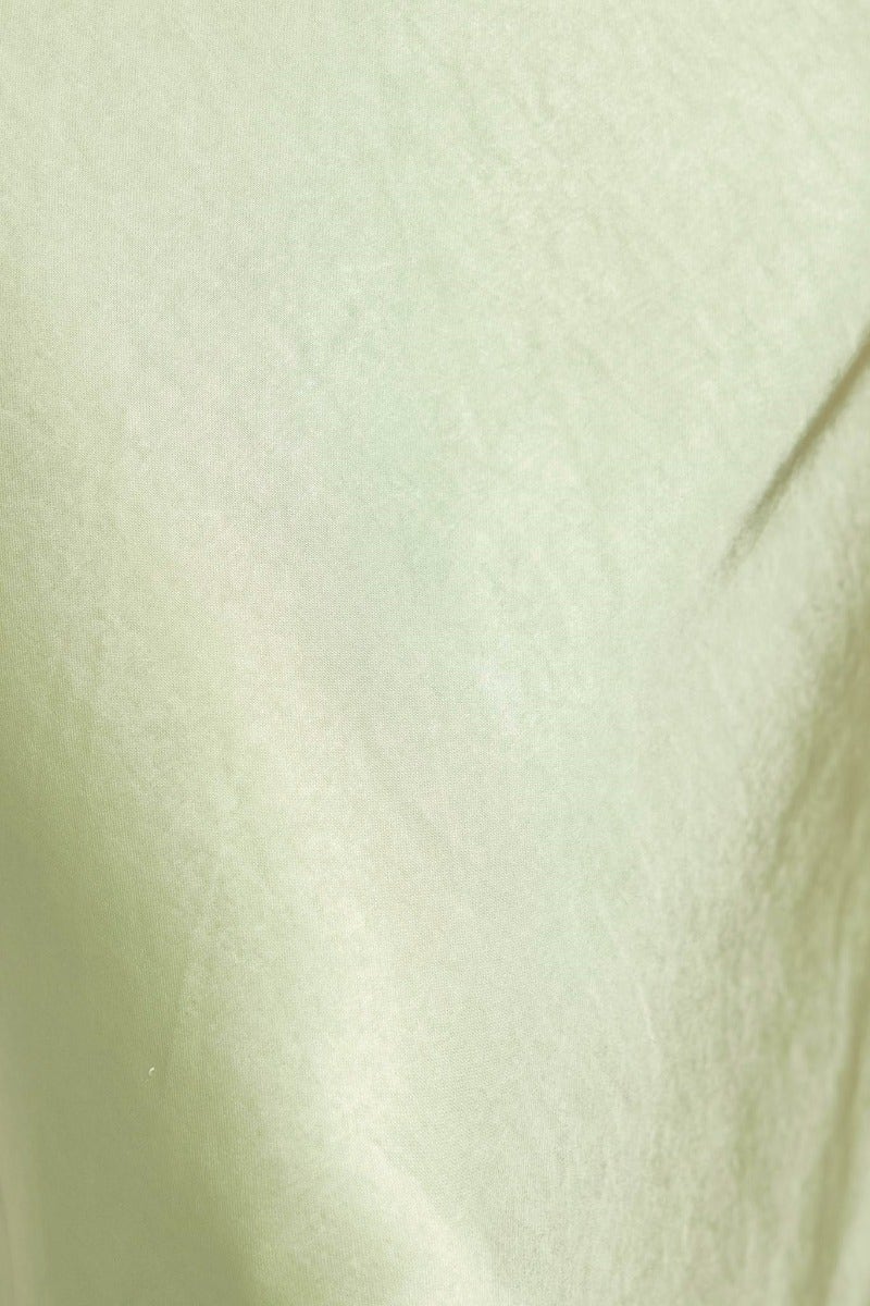 Close-up of the smooth, light green fabric of a satin maxi dress with soft sheen and texture.