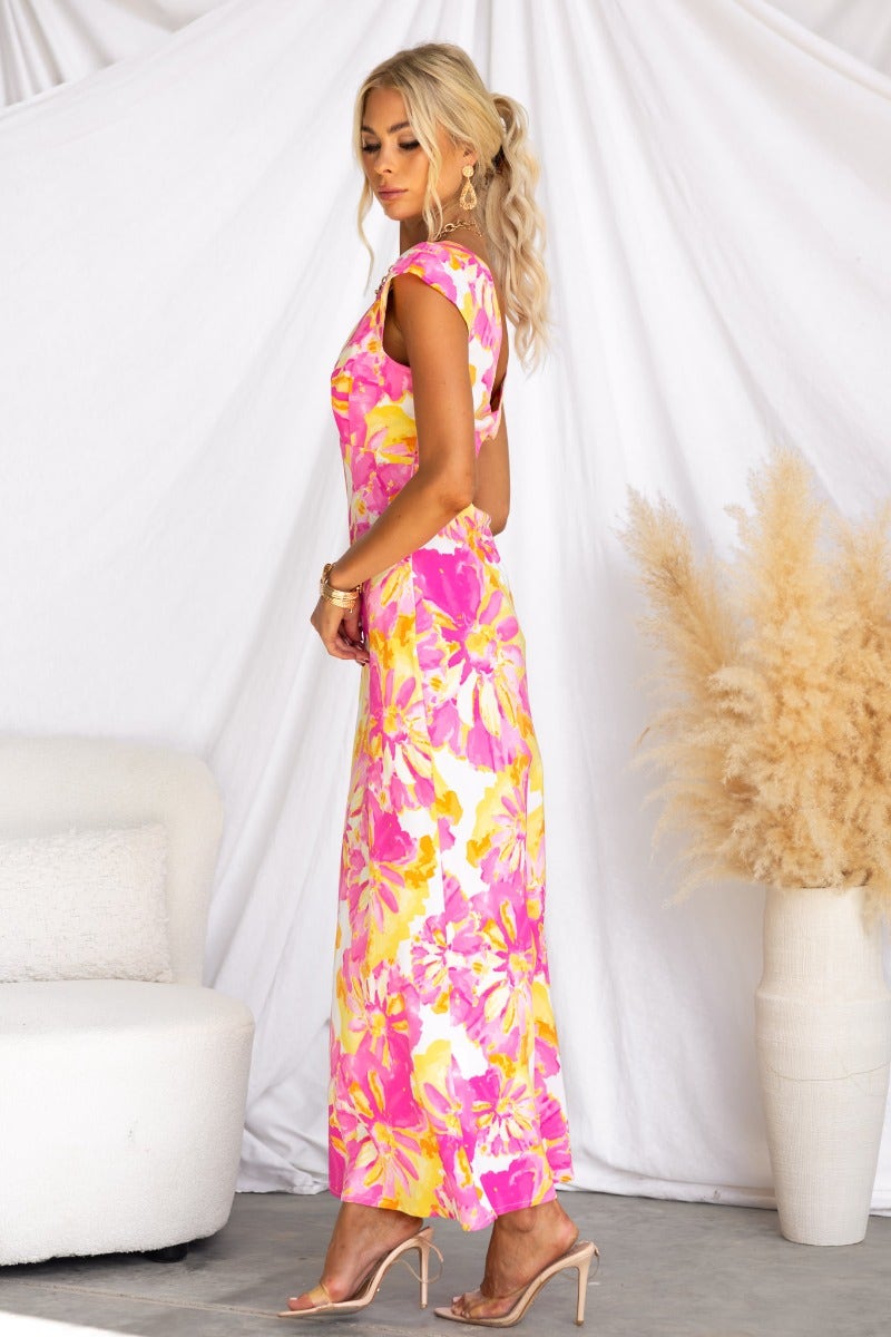Model wearing a floral print Live In Colour maxi dress with V-neckline and cap sleeves, showcasing a vibrant design.