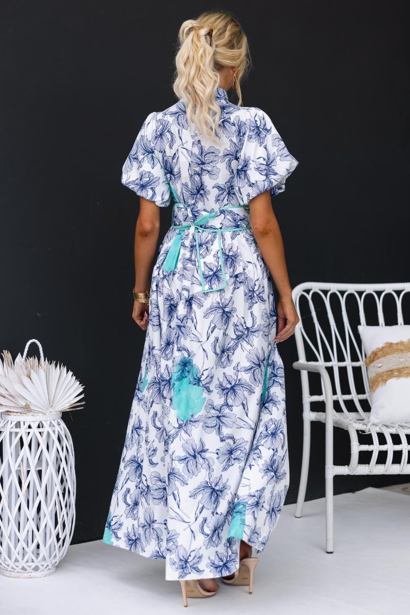 Back view of Younger Now floral print maxi dress with a high neckline and fabric belt, styled in a chic setting.