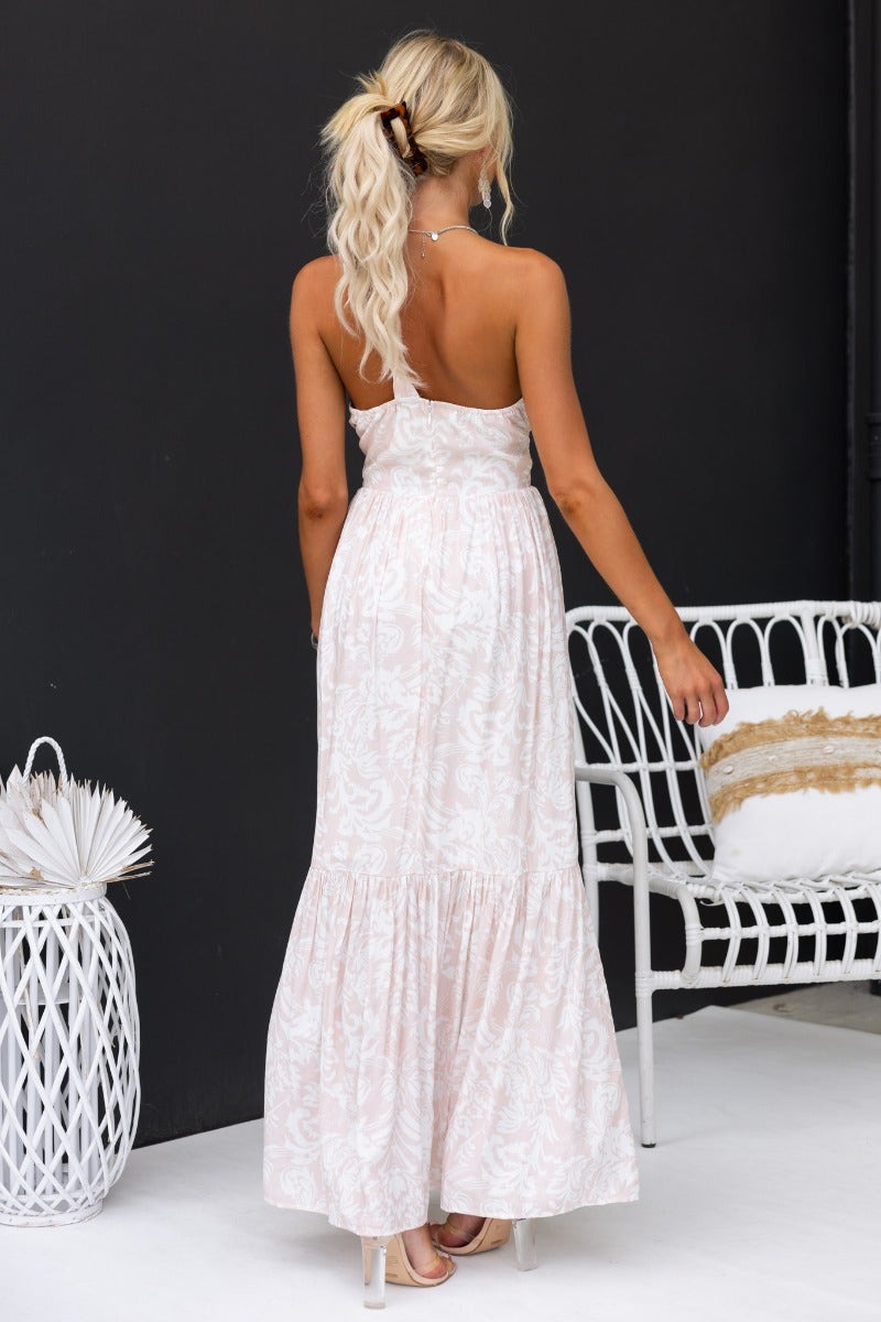Back view of a woman in a floral print one-shoulder maxi dress, showcasing the elegant design and cut-out details.