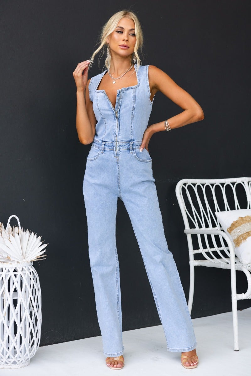 Model wearing Kentwell Denim Jumpsuit featuring a zip-up front and pockets, styled against a dark background.